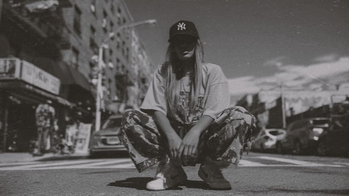 Collector in a New York cap crouching on the street
